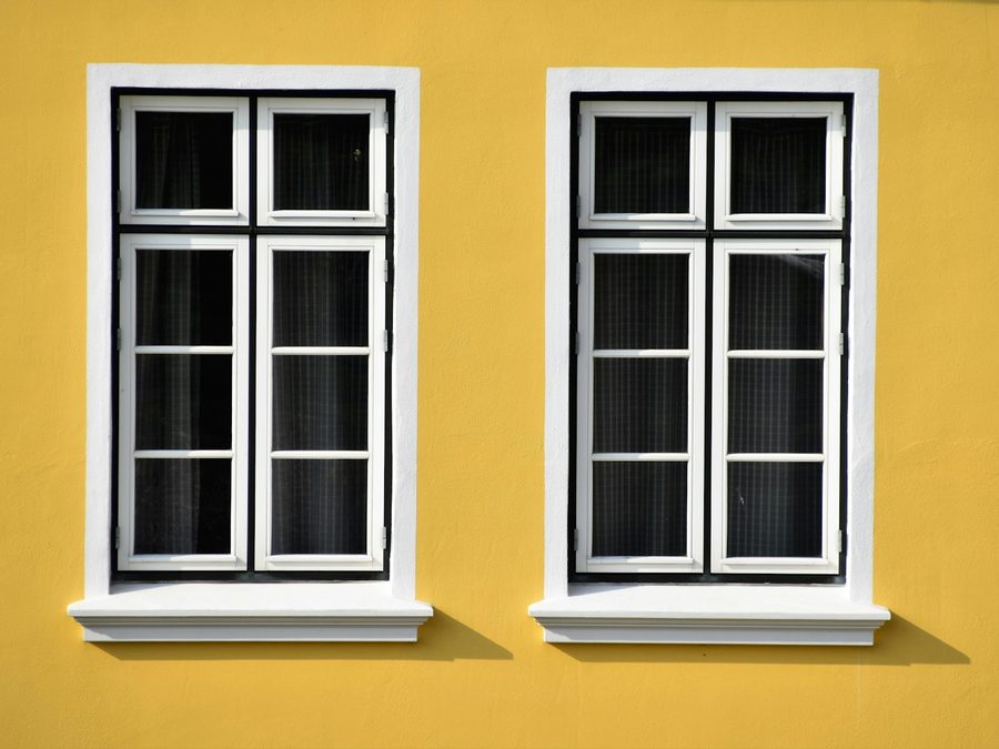 Twee witte kozijnen in een okergele gevel